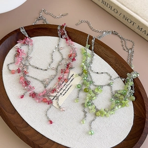 Detail of pink and green floral beaded layered necklaces on a wooden tray