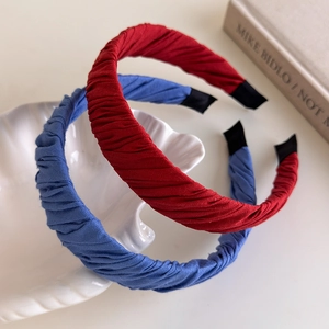 Red and blue pleated fabric headbands displayed on a white shell-shaped porcelain plate
