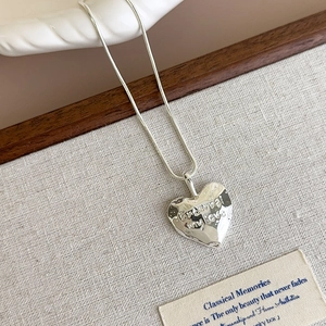 Close-up of silver heart pendant with hammered texture and Eternal my love engraving