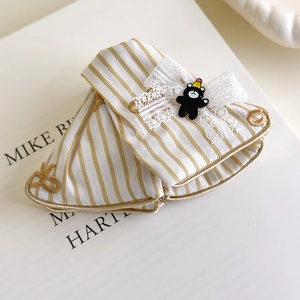 Détail de la pince à cheveux rayée jaune avec petit ours et bordure en dentelle blanche