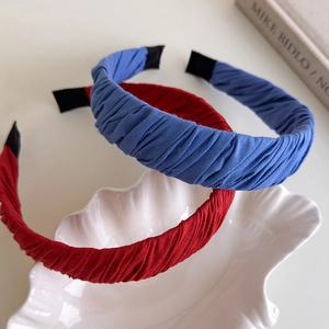 Detail of red and blue pleated fabric headbands displayed on a white shell decorative tray