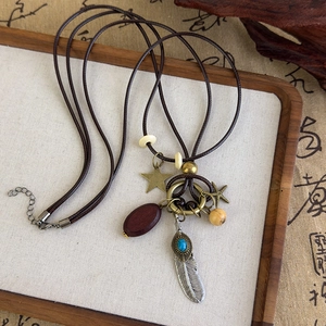 Détail de collier ethnique vintage avec étoiles en bronze, plumes argentées et perles