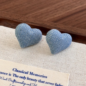 Macro view of heart-shaped denim fabric stud earrings with white polka dots and retro style