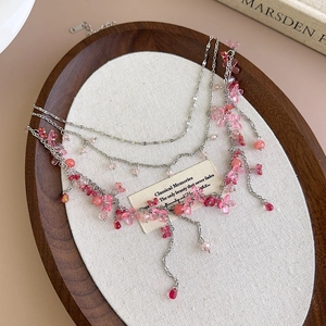 Detailed view of layered silver necklace featuring pink resin flowers and beaded charms