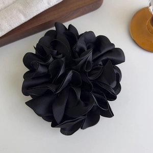 Vue macro d'un grand chouchou en satin noir avec textures de pétales de tissu superposés