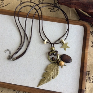 Détails du pendentif plume bohème avec perles en bois sur un collier en cordon tressé