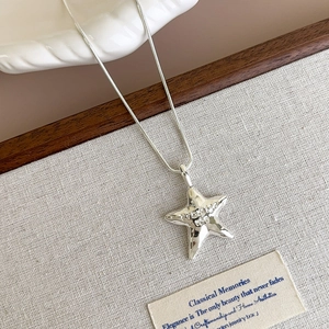 Detailed macro view of silver starfish pendant with textured hammer finish and snake chain