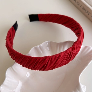Detail of red pleated fabric headband with smooth texture in a white shell dish