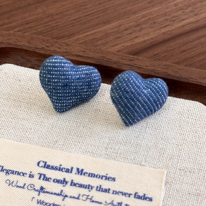 Macro shot of blue denim heart earrings showing detailed fabric texture and retro style