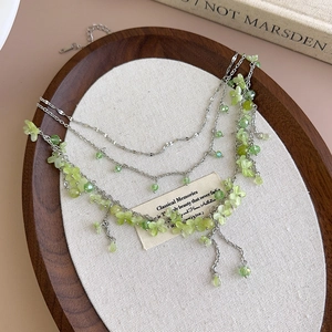Macro view of multi-layered silver chains with light green petal beads and floral details