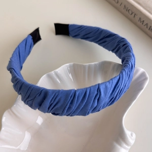 Detail of blue pleated fabric headband with soft texture on a white shell decorative tray