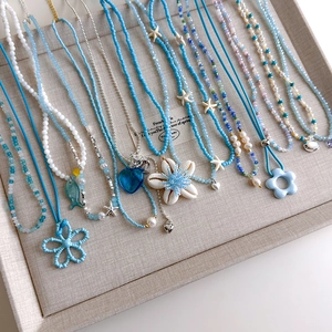 Detail von blauen Perlenketten mit Muscheln und Seesternen für den Sommerlook