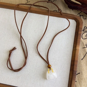 Détail macro d'un pendentif en pierre en forme de sac sur un collier en cordon tressé
