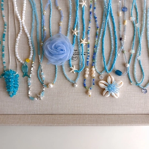 Details von blauen Perlenketten mit Muscheln, Seesternen und Stoffblumen