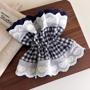 Detail of navy blue plaid fabric scrunchie with white heart lace embroidery on wood