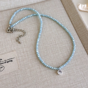 Detail einer hellblauen facettierten Perlenkette mit Zirkonia-Anhänger und Muscheldekor