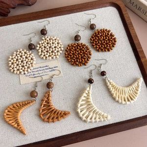 Detail of bohemian handmade wooden bead and straw woven earrings in natural tones