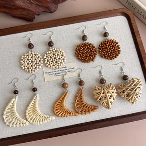 Detailed view of handmade woven geometric wooden earrings on a rustic display tray