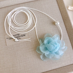 Detail von hellblauer Organza-Blume mit weißer Kordel und einer Perle am Anhänger