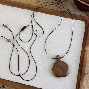 Détail du pendentif en bois de style vintage avec grain naturel et cordon ajustable