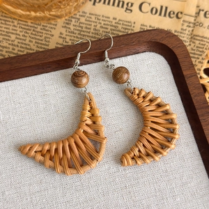 Detail von handgefertigten sichelförmigen Rattan-Ohrringen mit Holzperlen auf Vintage-Stil