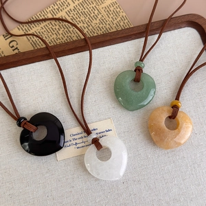 Detailed view of four heart-shaped natural stone pendants on rustic cord necklaces
