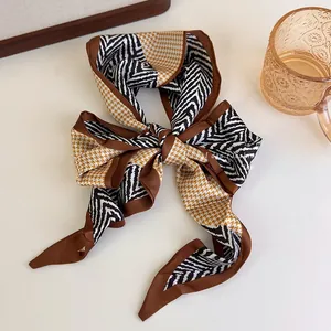 Close-up of a stylish houndstooth and zebra print silk scarf tied in a bow knot