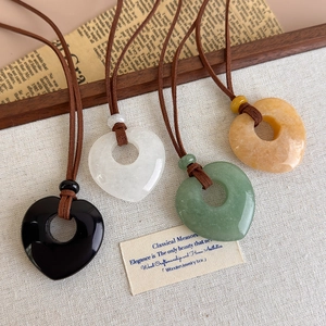 Long natural stone heart pendant necklace set with braided leather rope on rustic linen