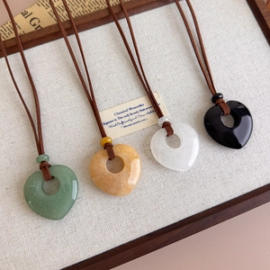 Detail of four heart-shaped natural stone pendants in green, white, black, and amber yellow