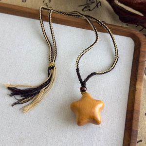 Détail macro du pendentif étoile en bois de santal avec cordon tressé et pompons décoratifs