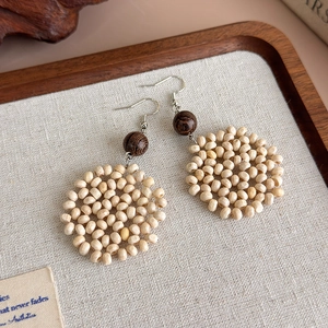 Detailed macro shot of handmade wood bead drop earrings featuring a floral sphere design
