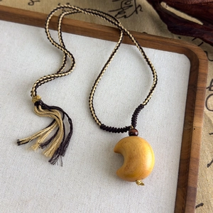 Gros plan d'un pendentif ethnique en forme de croissant avec corde tressée et pompon