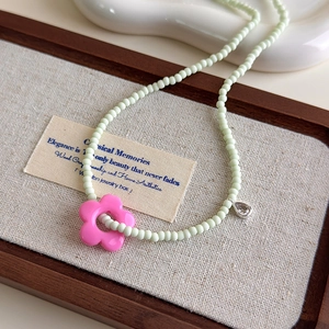 Collier de perles menthe avec pendentif fleur rose et petite breloque argentée