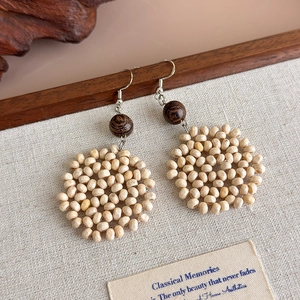Detailed view of handmade woven wooden drop earrings on a natural linen background