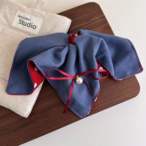 Detail von Denim Haargummi mit Punkten, roter Schleife und Perle auf Holztablett