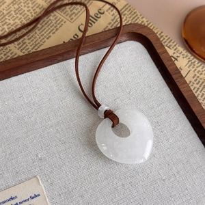 Detail of white natural stone heart pendant on a vintage brown cord necklace