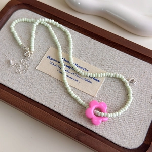 Détail du collier de perles vert menthe avec pendentif fleur rose et fermoir mousqueton