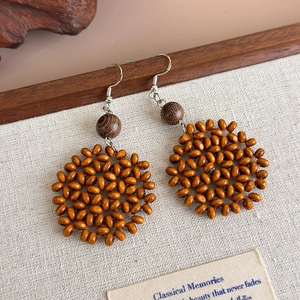 Macro view of handmade woven wooden bead earrings on a rustic burlap backdrop