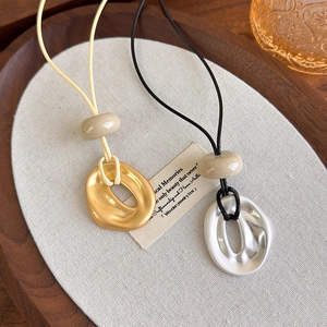 Detailed view of geometric irregular pendants on cord necklaces with ceramic beads