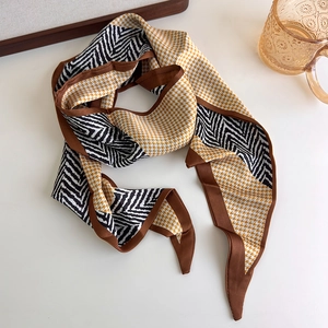Close-up of narrow silk scarf with yellow houndstooth and geometric patterns for waist styling