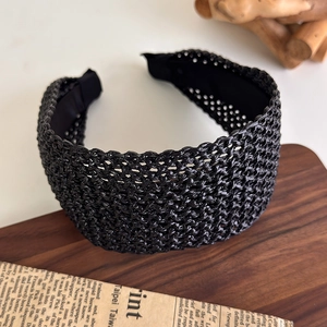 Détail du serre-tête tressé noir avec texture de maille fine et design rétro élégant