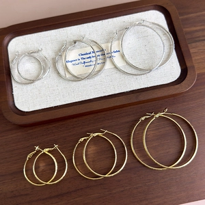 Detailed macro view of gold and silver textured hoop earrings in various sizes on a tray