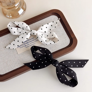 Barrettes à cheveux à nœuds à pois noirs et blancs sur un plateau en lin