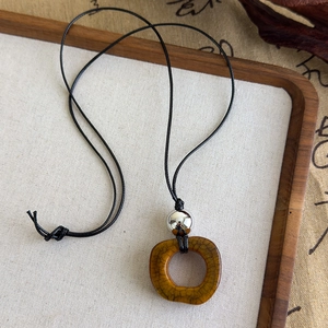 Détail d'un pendentif en céramique à glaçure craquelée sur un cordon noir tressé