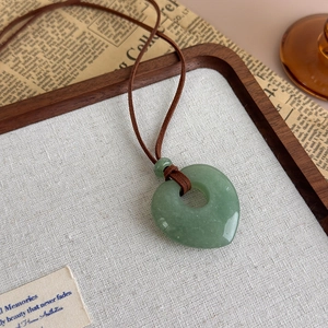 Detail of green natural stone heart pendant on a vintage style brown cord necklace
