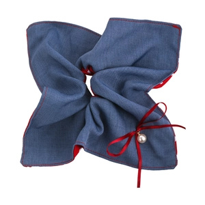 Detail eines blauen Denim-Haargummis mit roter Naht, Seidenschleife und Perlenanhänger