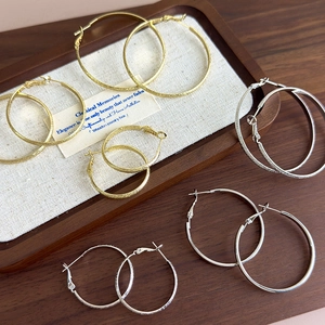 Elegant gold and silver hoop earrings with textured and polished finishes on wooden tray