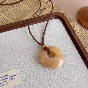 Macro view of natural stone heart pendant with brown cord on a vintage background