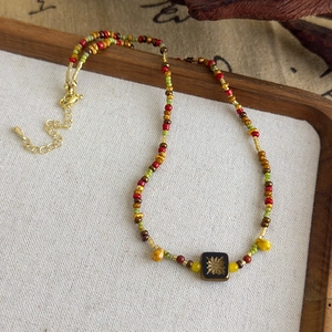 Détail du collier de perles fait main avec pendentif soleil doré et fermoir mousqueton