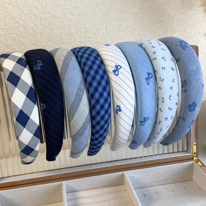 Detailed close-up of 8-piece blue plaid and floral bow headband set in a wooden organizer